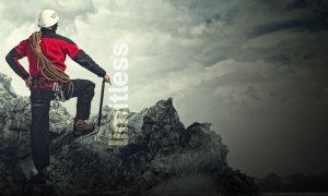 A man with rock climing gear on at the top of a mountain top with the word limitless over it.