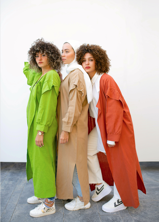 Three women standing together with three different colored jackets.