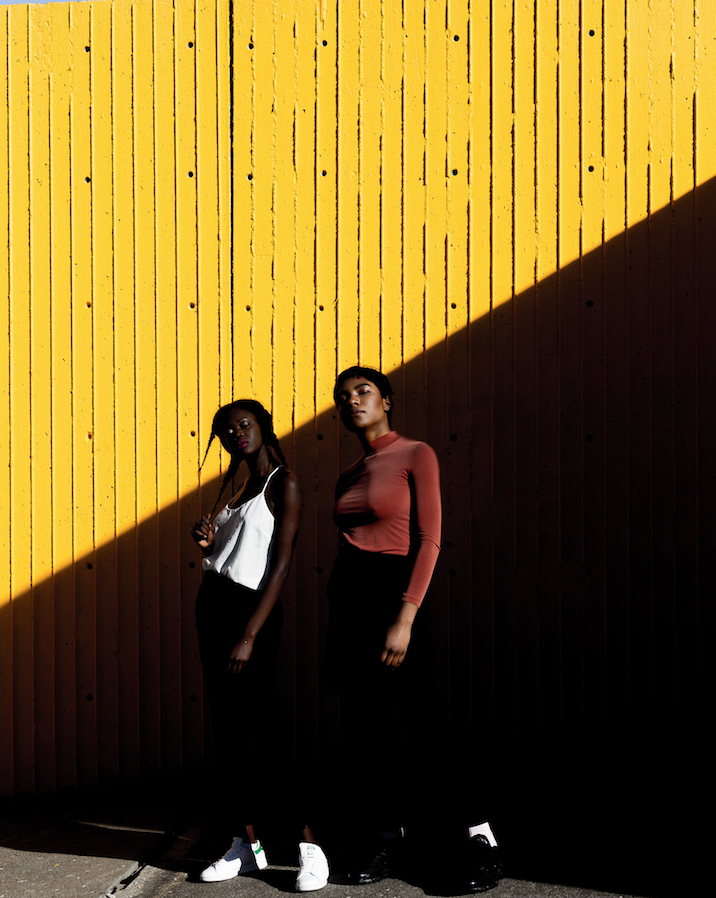 Models standing in front of a background with a sharp shadow going down the middle. 