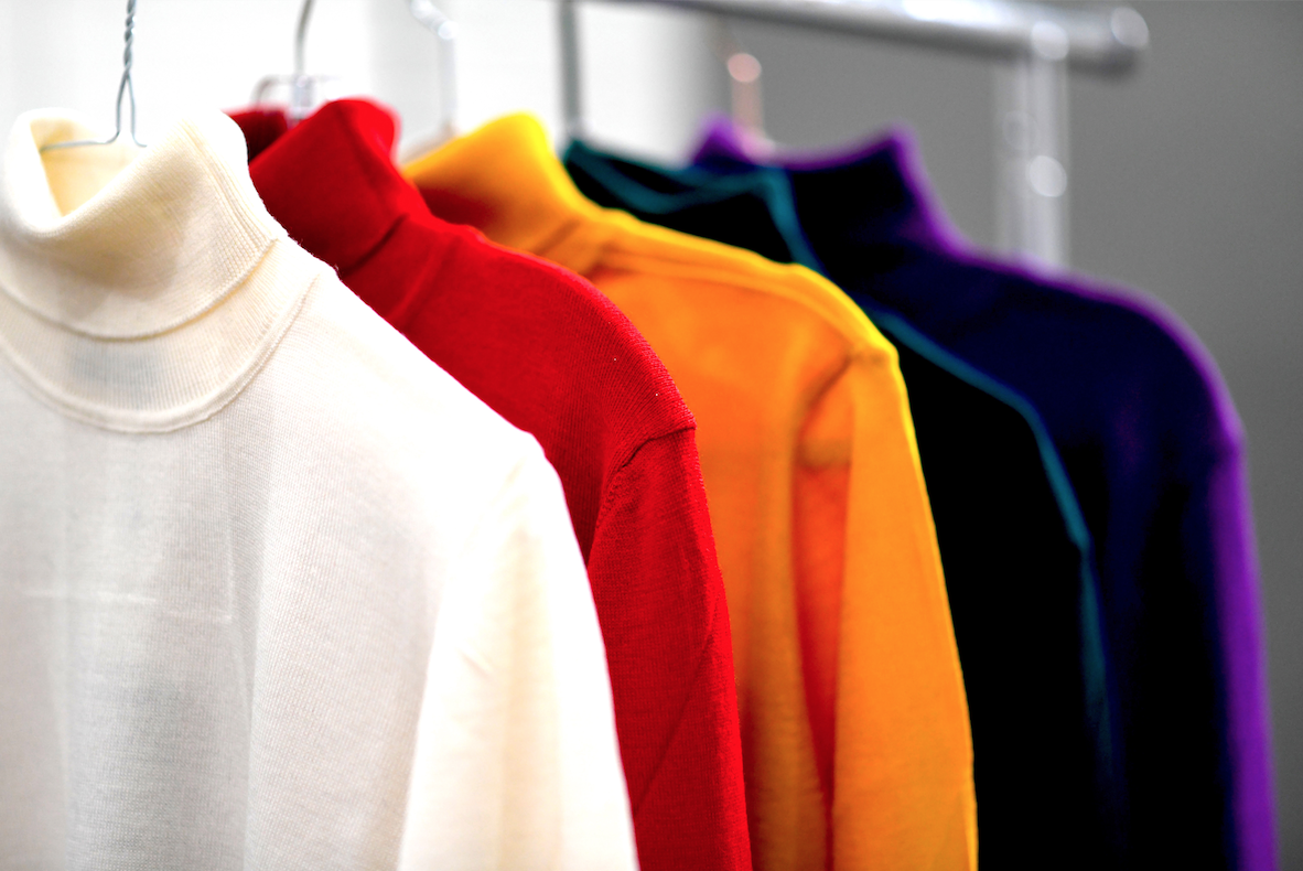 A white, red, orange, blue and purple and turtle neck on a clothing rack