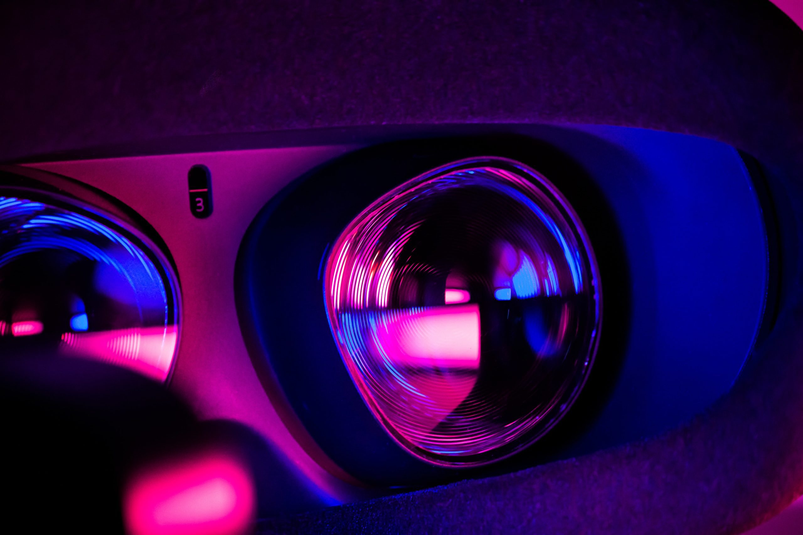 Close up look of a projector lens, with pink and blue tones. 