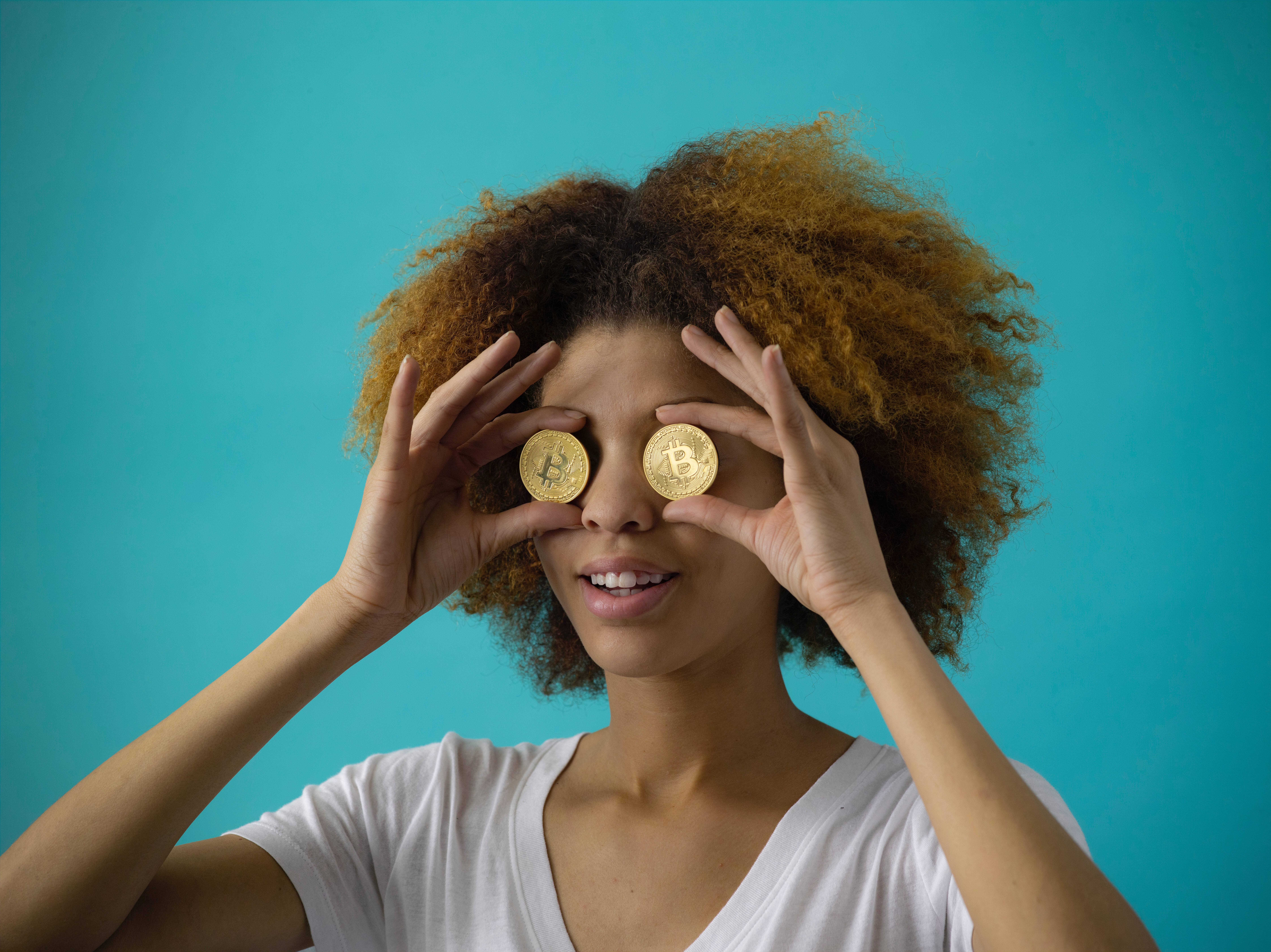 A women with two money coins over both her eyes. The background is blue.