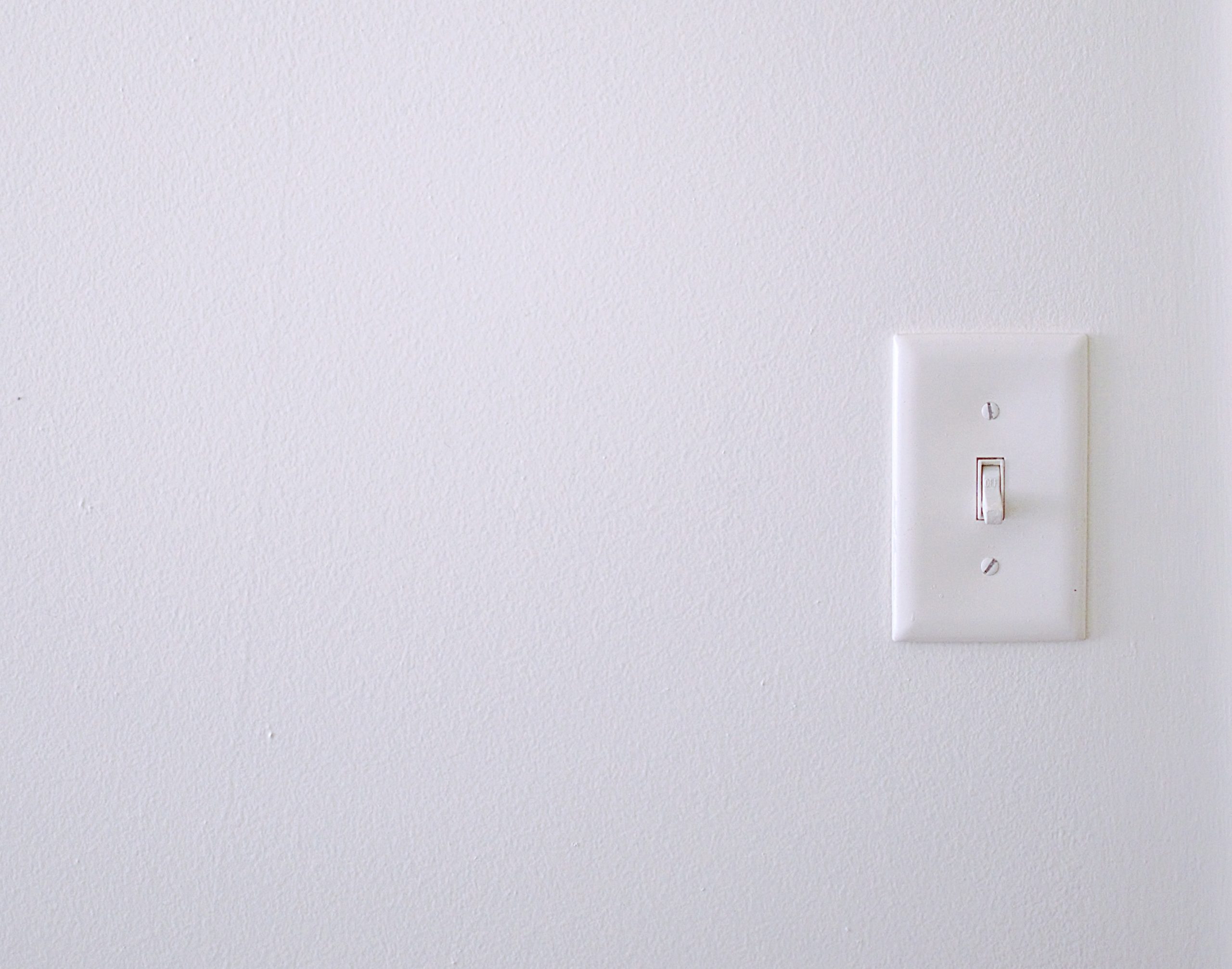 White wall with a white light switch on the right side of the frame