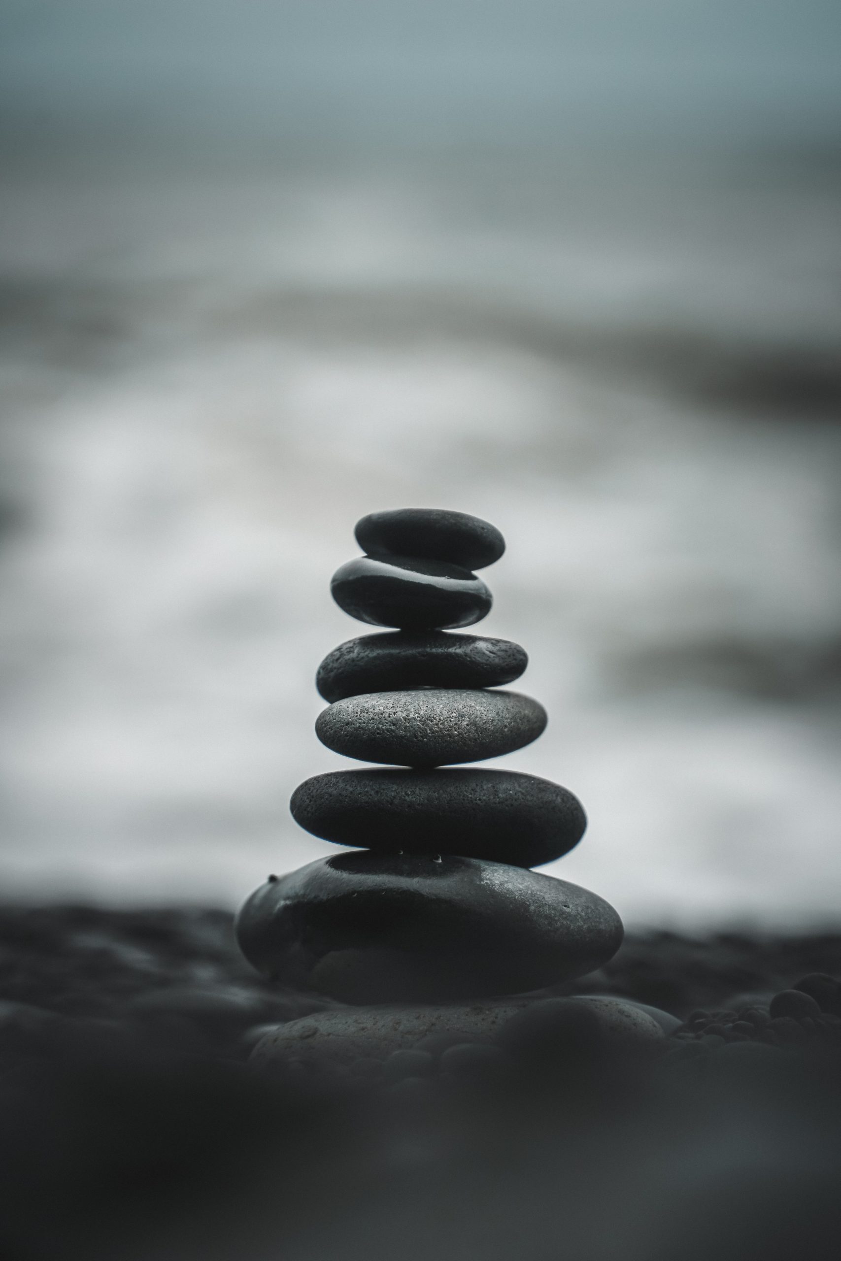 Black and white image with grey tones of stacked round smooth rocks. 