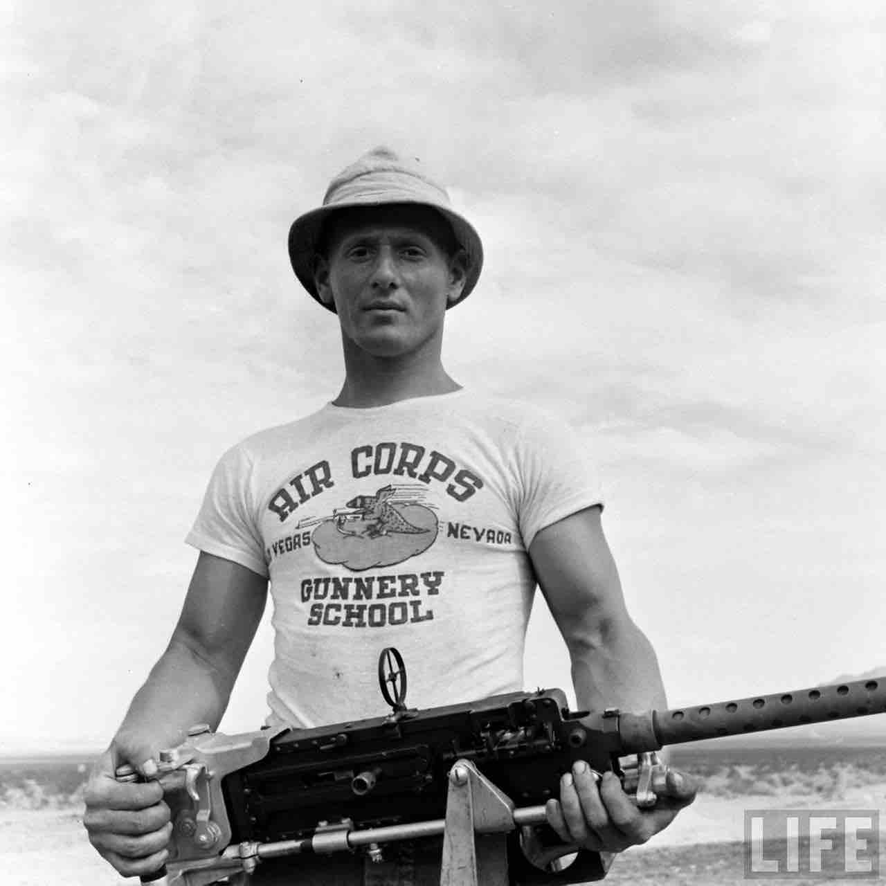 Photo from Life Magazine from 1942 of a A student with a T-shirt that says the Gunnery School holding a firearm. 