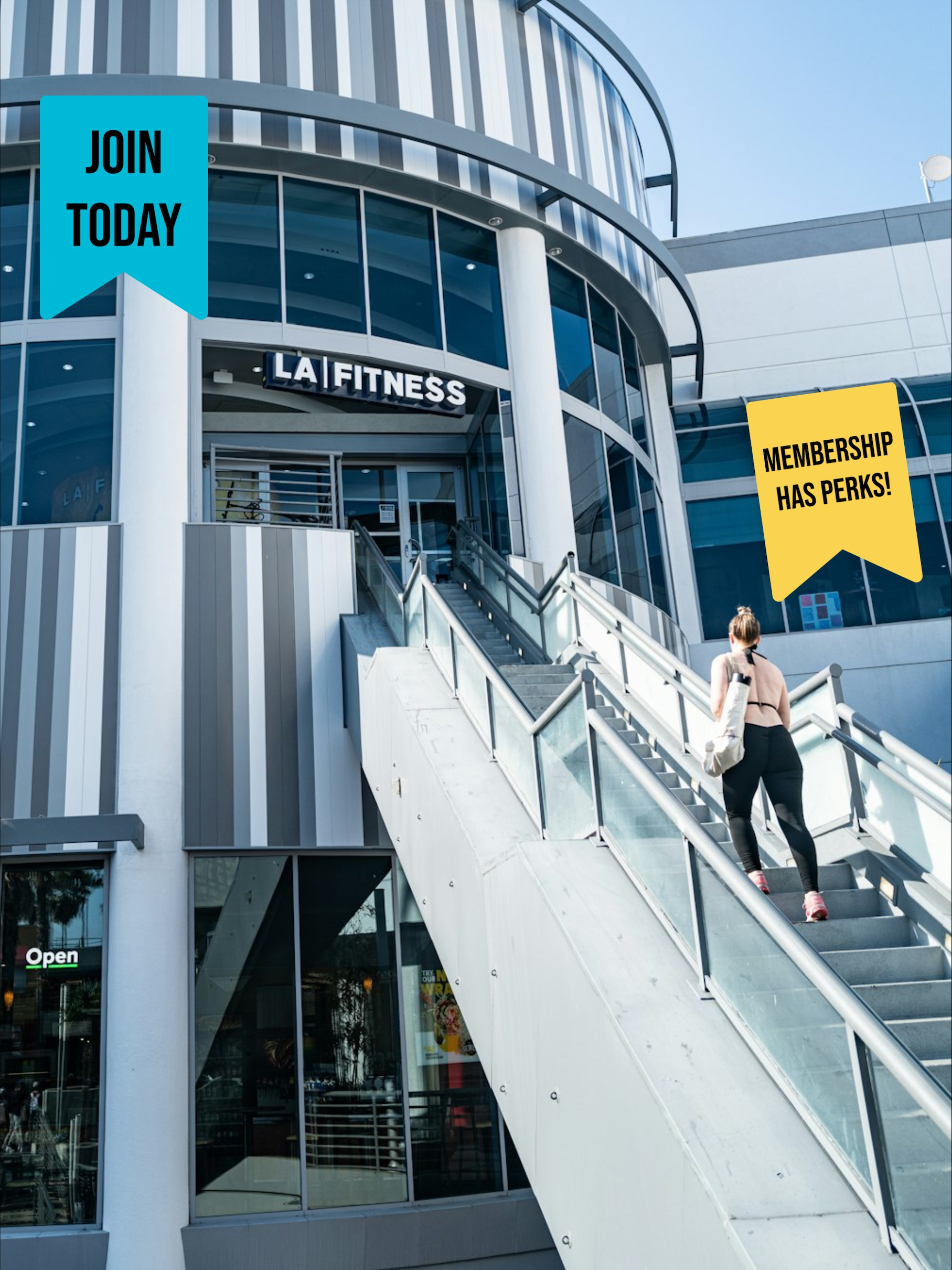 A photo of a women going up the stairs to LA Fitness