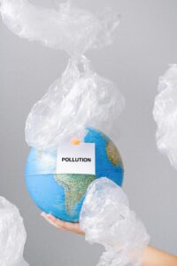 A world globe with the words pollution on it and trash bags flying everywhere