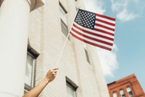 A hand out a window holding up an american flag
