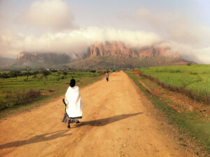 A photo of a woman walking down a dirt road